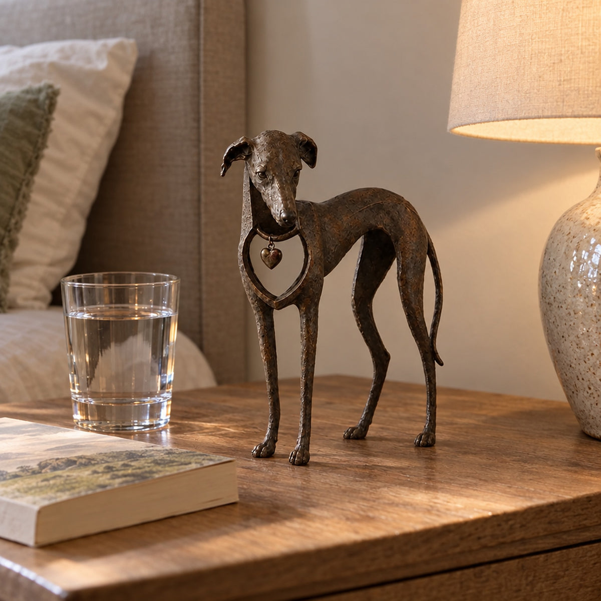 Hundfigur på sängbord bredvid vattenglas och bok