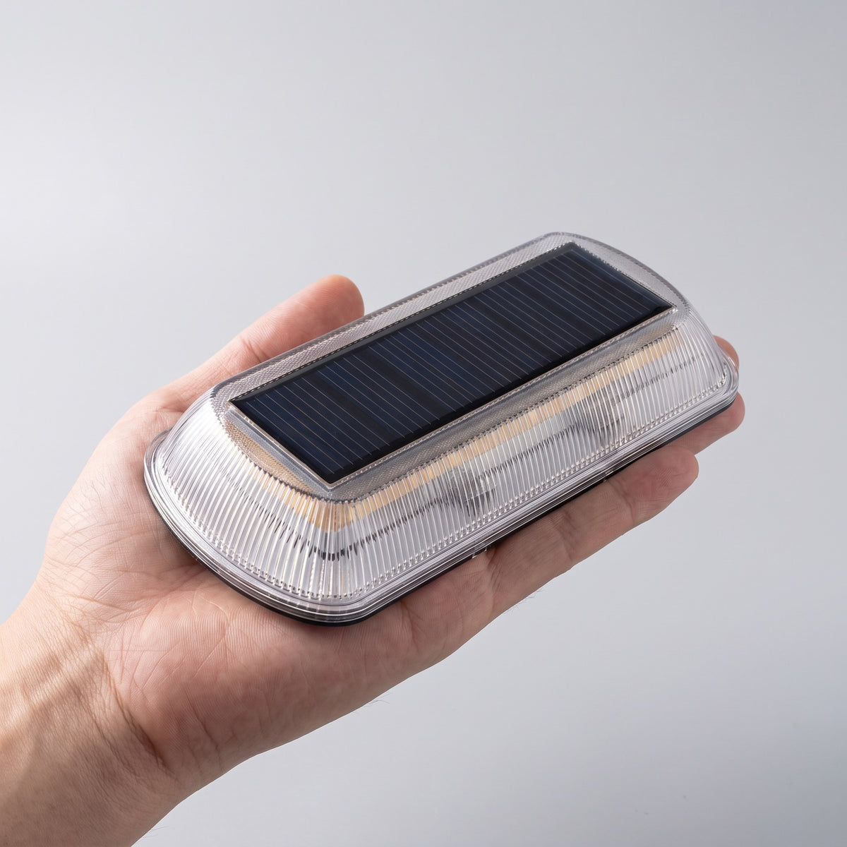 Hand håller en solcellslampa för trapp med solpanel synlig ovanifrån