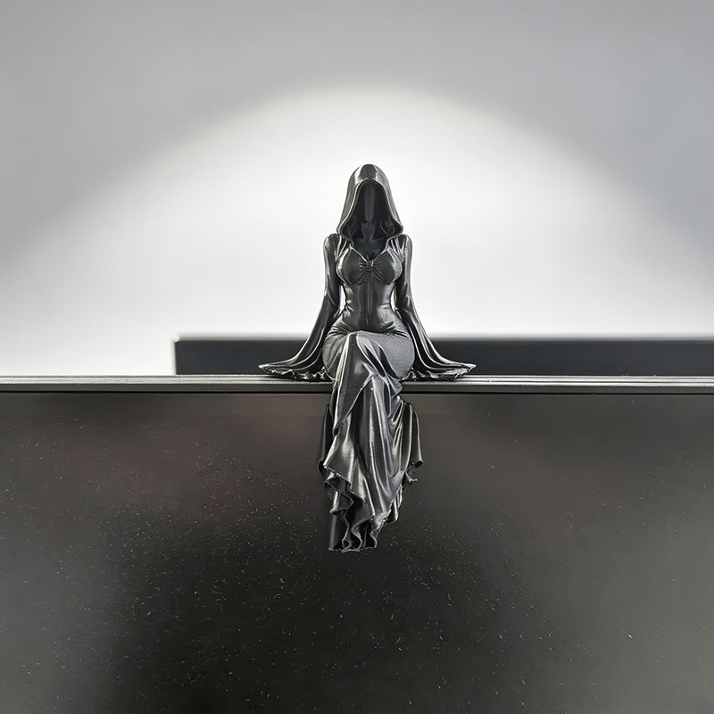 Kantsittande gotisk staty på monitor, svart figur med huva