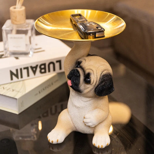 Mopsfigur med guldtallrik hållande bilnyckel på glasbord
