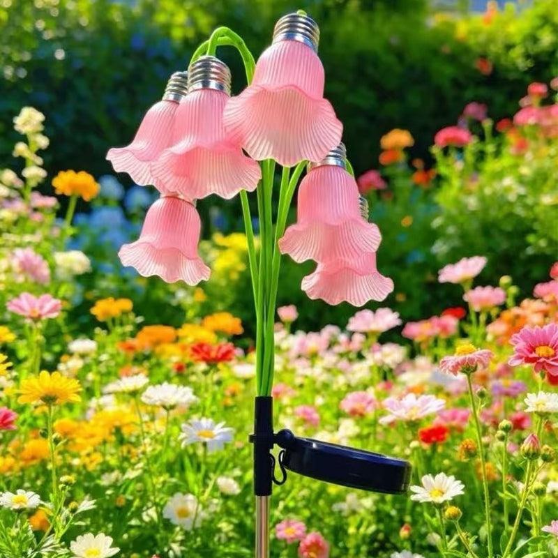 Rosa blomlampa med solcell bland blommor i trädgård
