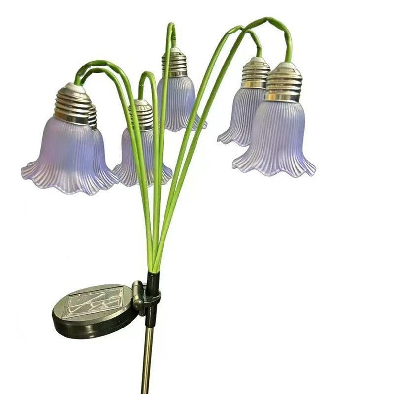 Lila solcellslampa med blomkupor mot vit bakgrund