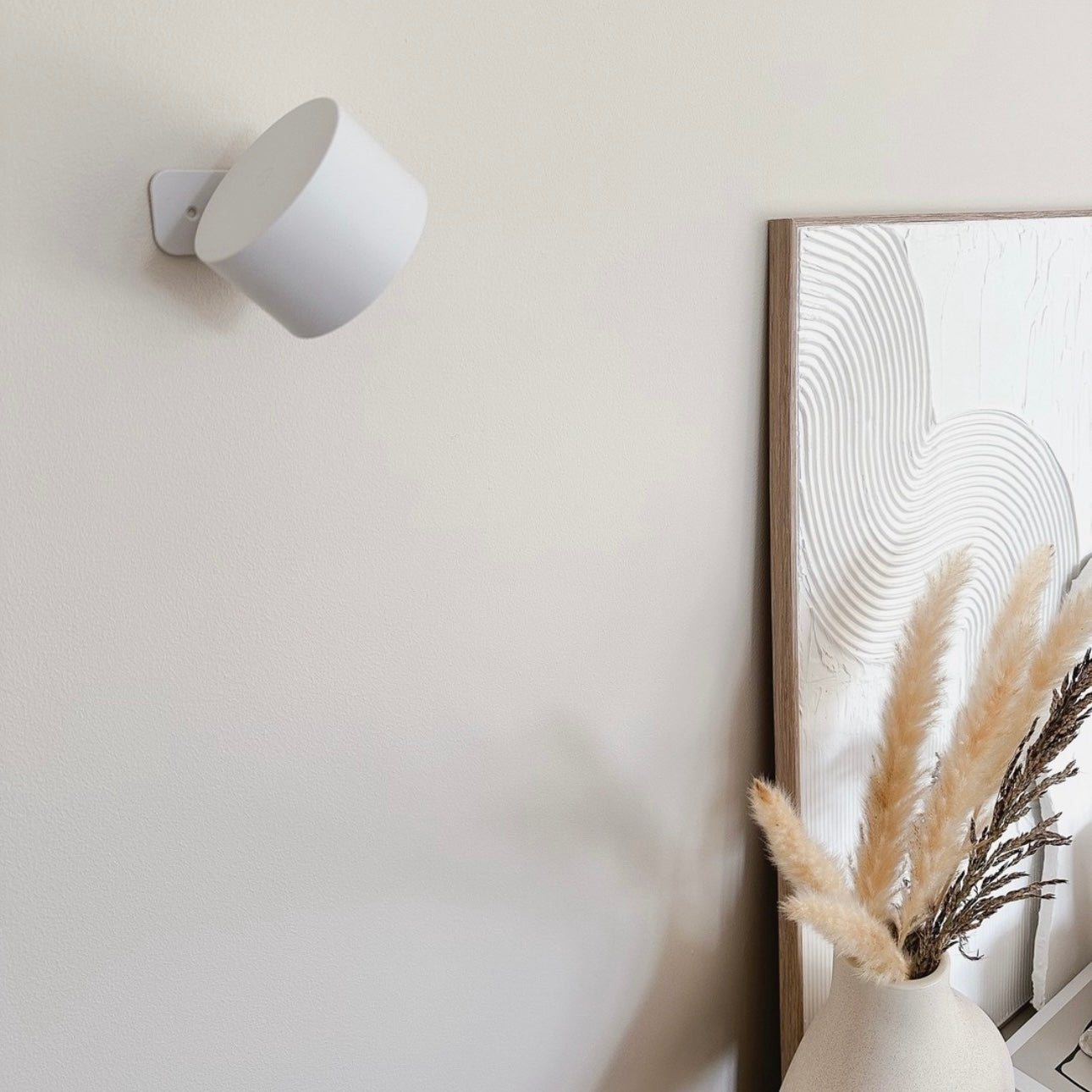 Skandinavisk vägglampa i vitt mot ljus vägg