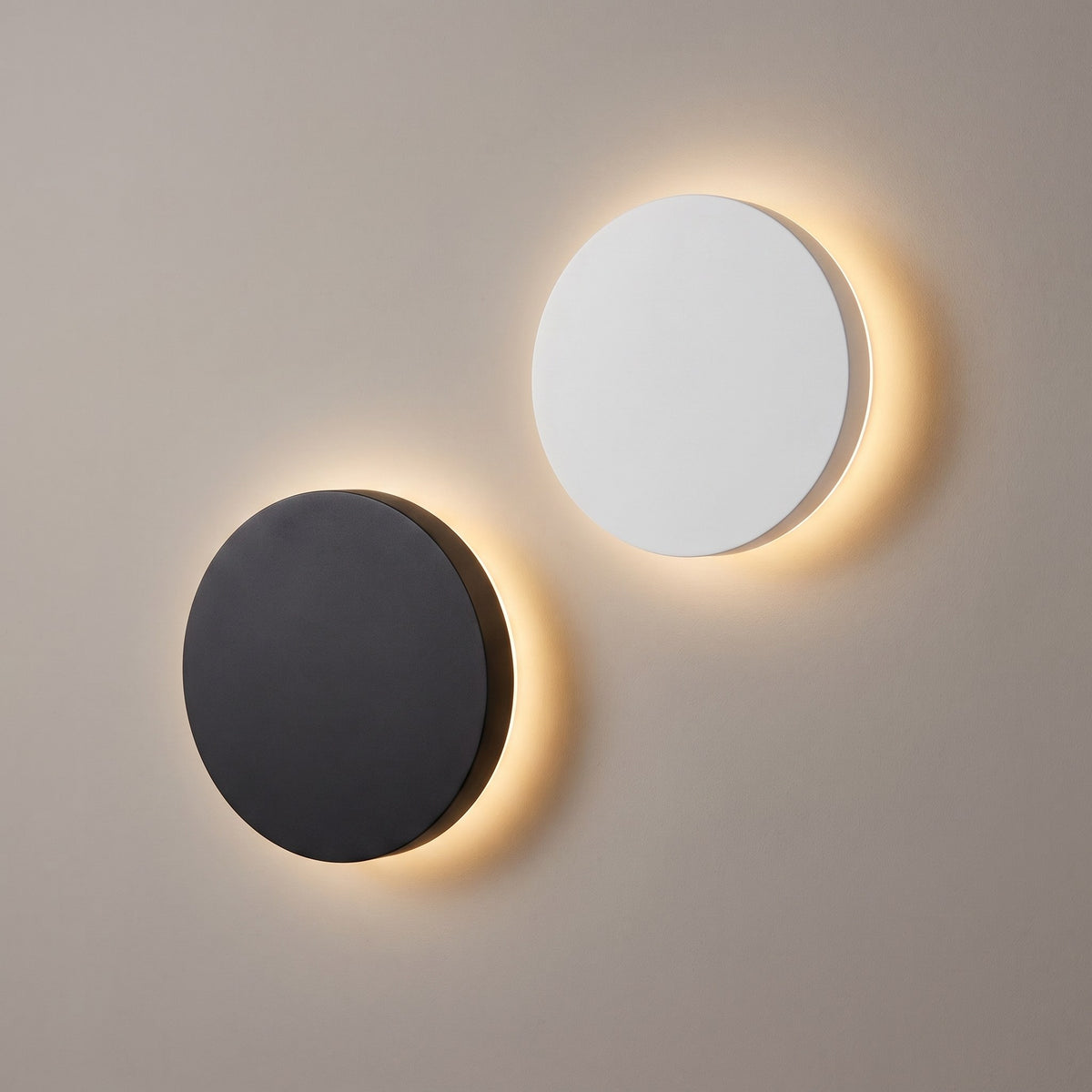 Rund LED-vägglampa i svart och vit – båda färgerna med bakgrundsbelysning