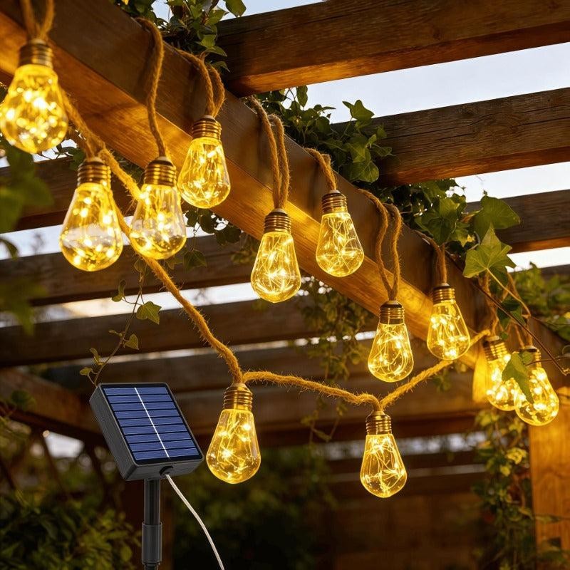 Solcellsdrivna ljusslingor i hamparep på pergola med solpanel i förgrunden