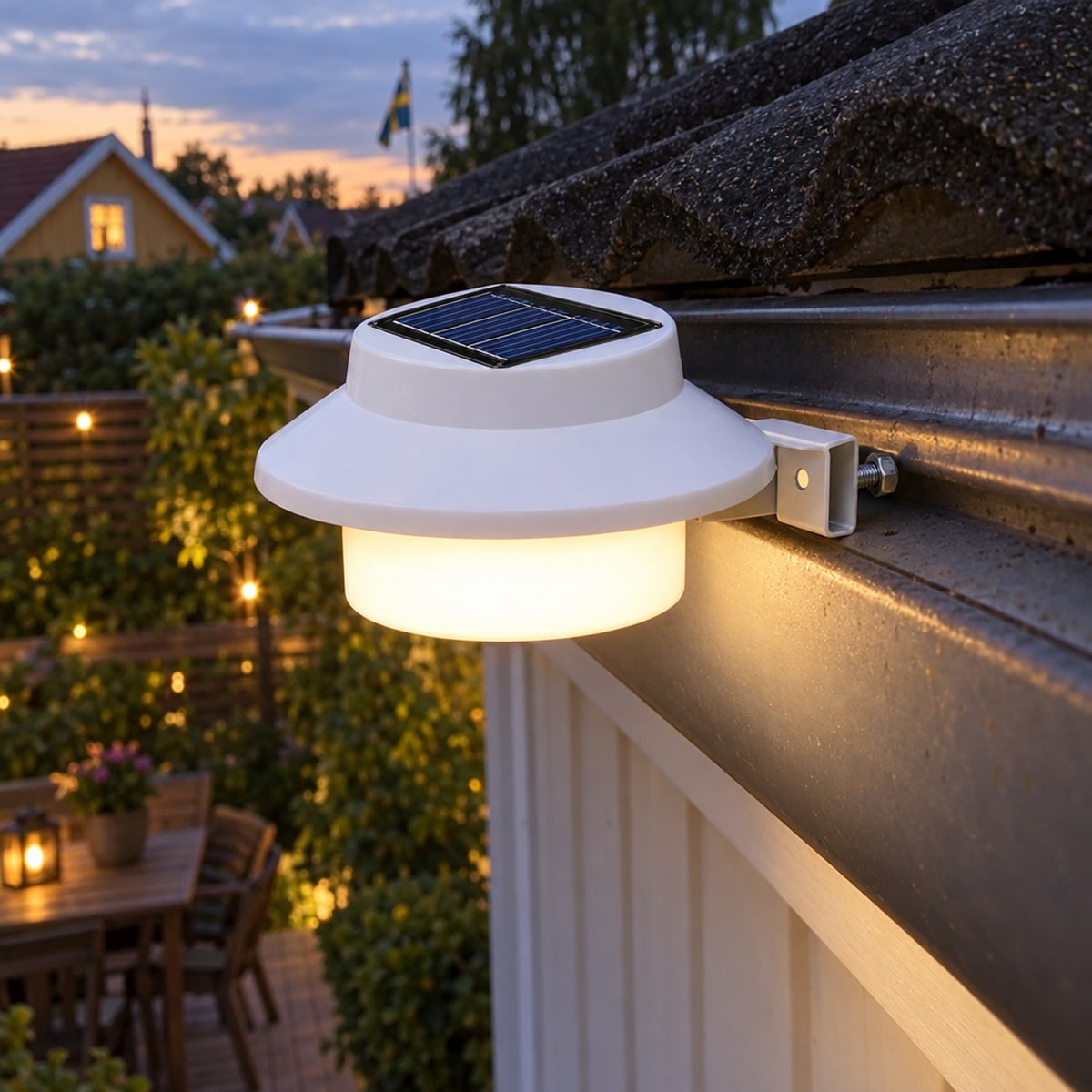 Vit solcellslampa på takränna en sommarkväll